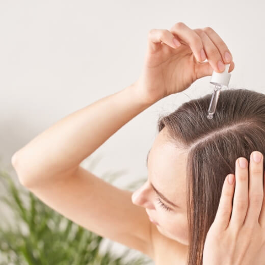 Woman Applying Topical Hair Care Product to Achieve Healthy Hair